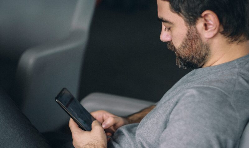 man seated and looking at cell phone