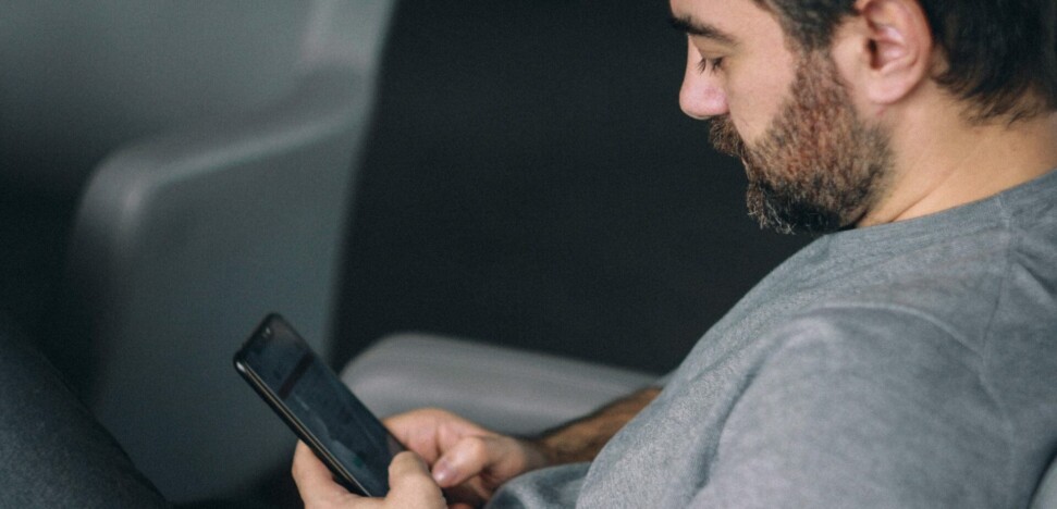 man seated and looking at cell phone