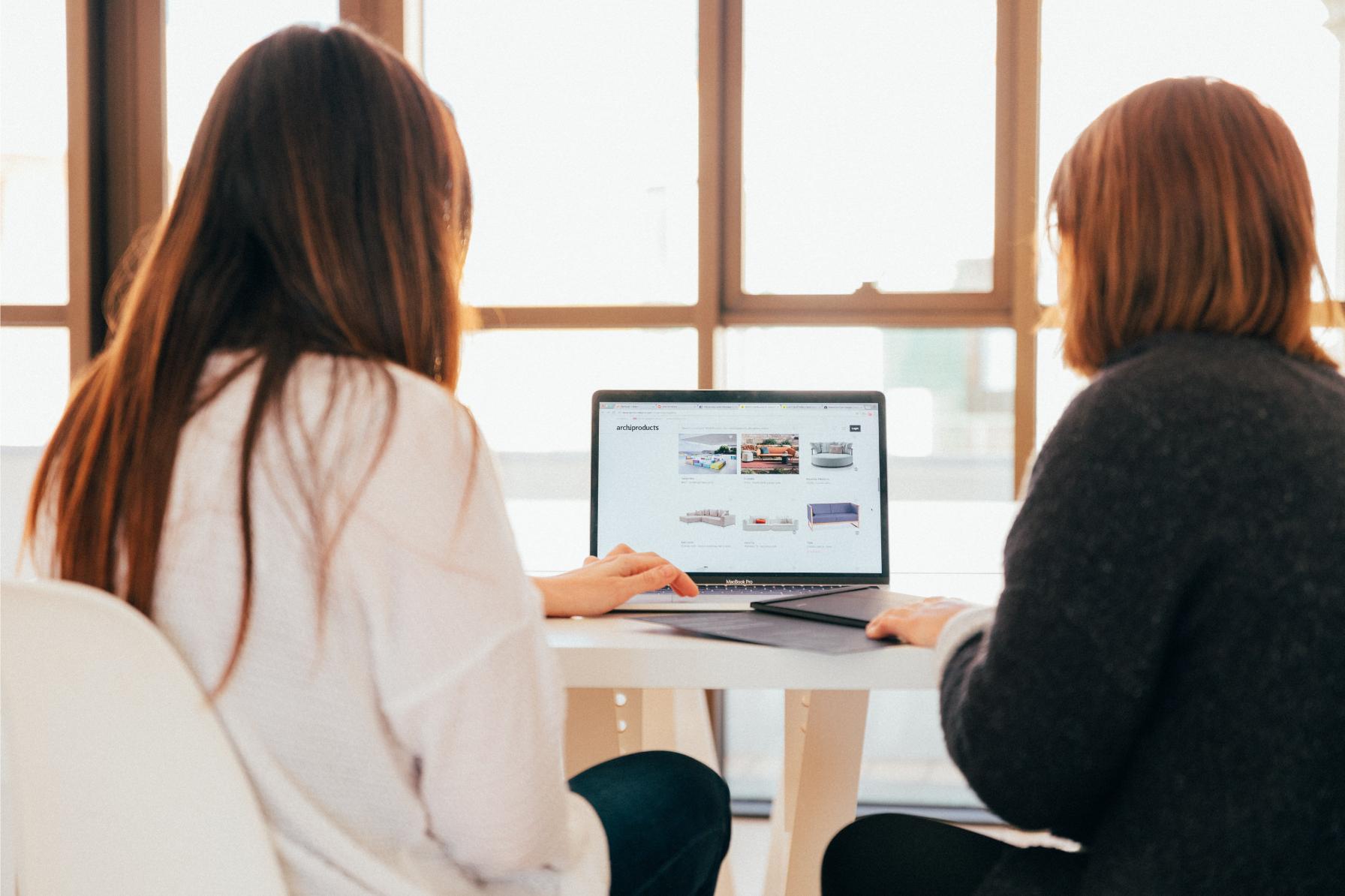 Two women look at a computer at fundraising financials.