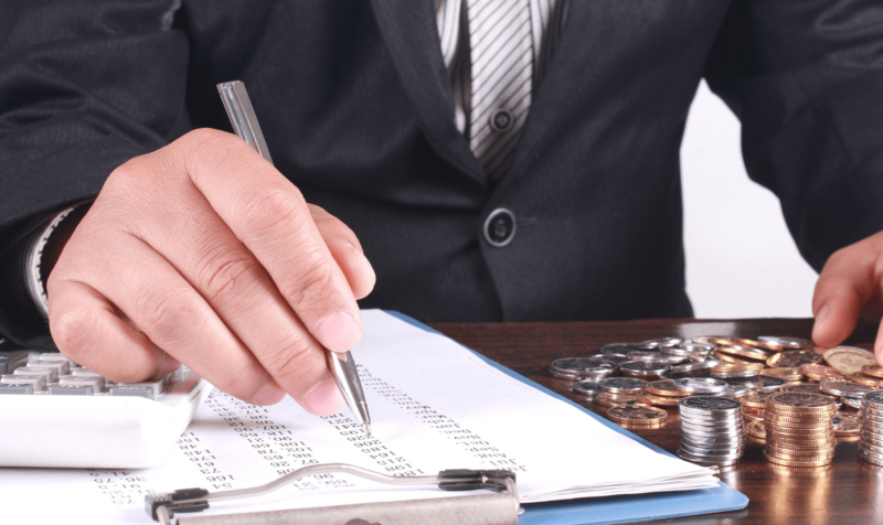 man with clipboard and coins on desktop